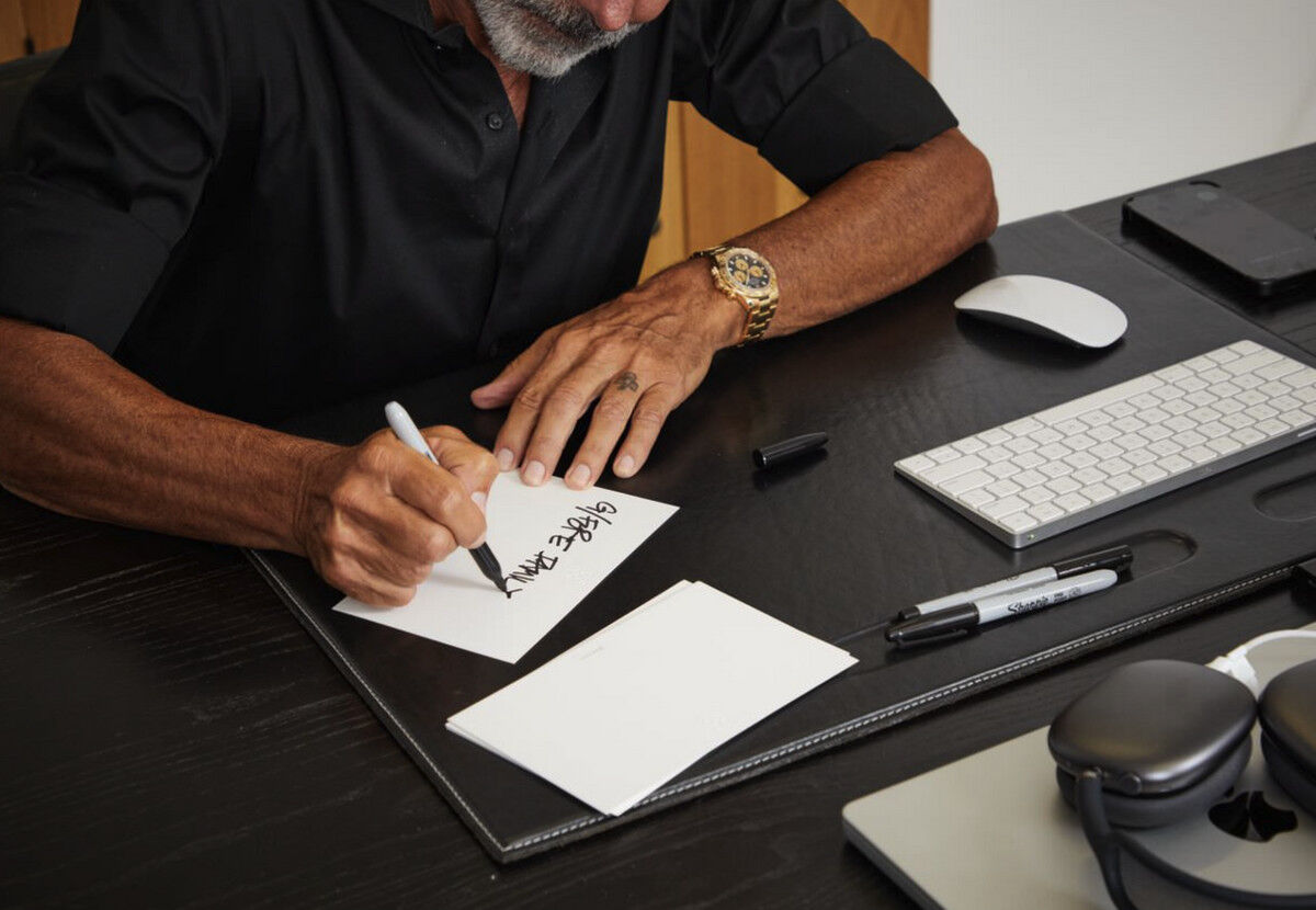 Mossimo at his desk, writing out a product style number on a piece of card-stock with sharpie.